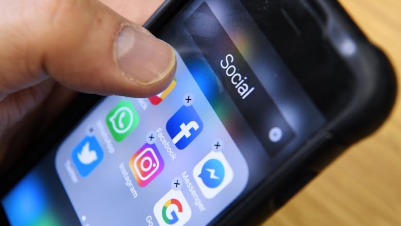 A close-up of a smartphone, showing some social media apps like Facebook, Instagram and WhatsApp.