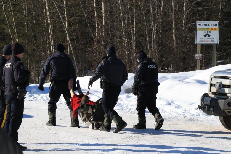 Police drag a person along a snowy road. 