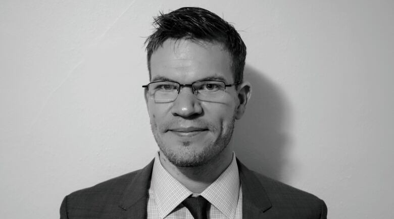 Headshot of man wearing suit and glasses