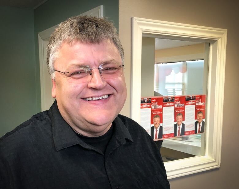 A man with glasses smiles and looks at the camera.