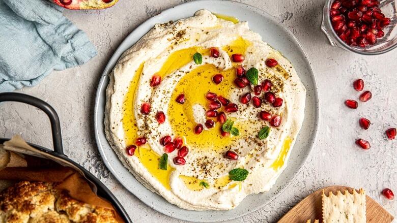 Overhead shot of a plate of cauliflower spread, garnished with pomegranate arils. 