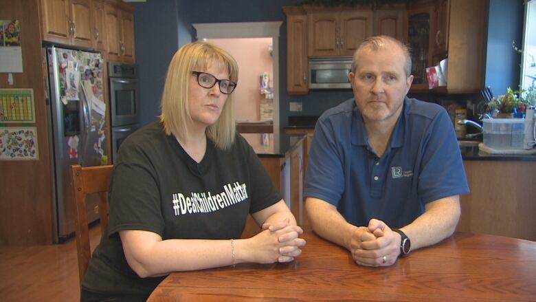 Kimberly and Todd Churchill sitting at their kitchen table, hands crossed, looking concerned.