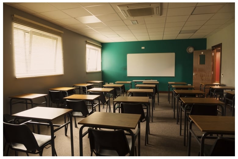 Desks are pictured in an empty classroom.