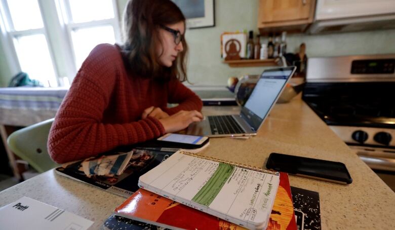 A student works on a laptop at a kitchen counter.