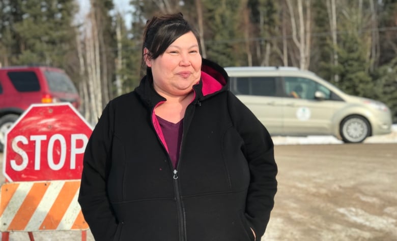 April Martel, chief of Kt'odeeche First Nation, stands in front a barricade and stop sign.