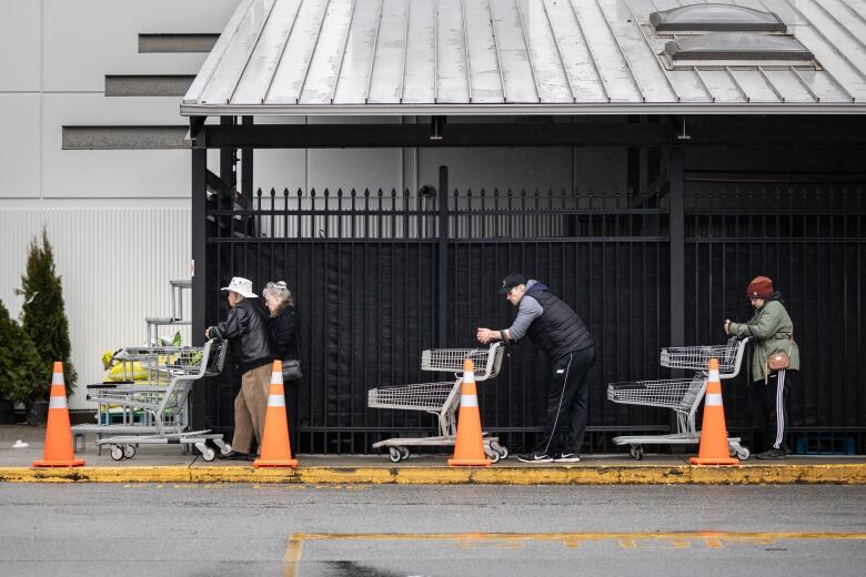 People line up outside a grocery store two metres apart.