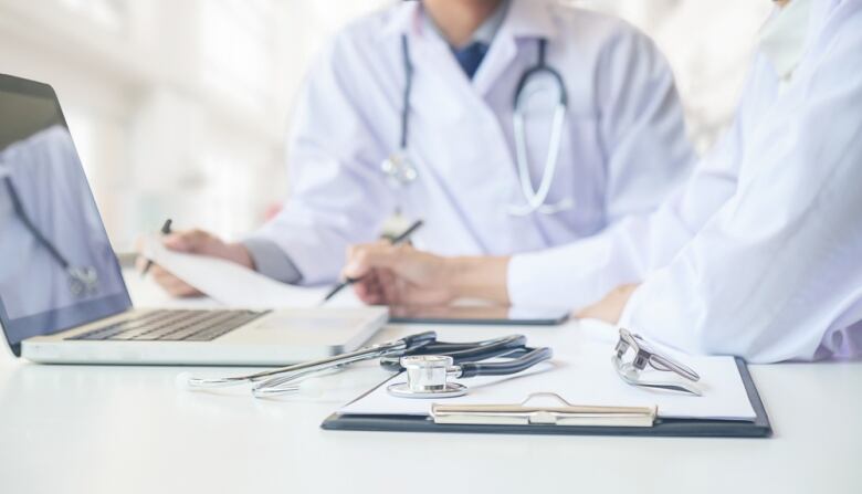 A stock image of doctors in lab coats working at a desk, with stethoscopes visible.