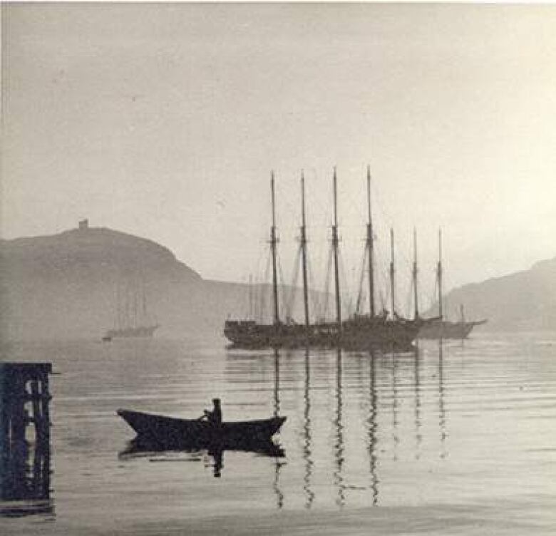 An archival photo shows two four-masted schooners, with a fisherman rowing a dory in the foreground. 