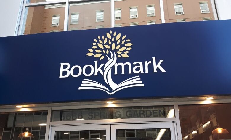 A navy blue store awning with the name of the store, Bookmark, is seen in this image of a storefront.