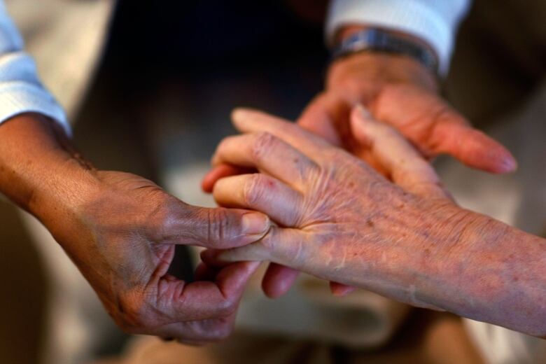 A closeup photo of a home health aide's hands massaging a senior's fingers.  