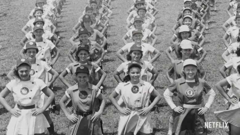 A black and white image of women lined up in several columns and rows, they are all wearing sporting attire.