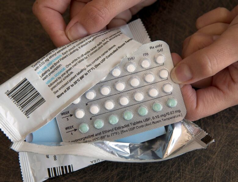 a person holds packets of white and blue pills