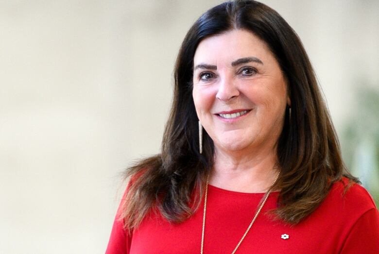 A woman is smiling and wearing a red shirt. 