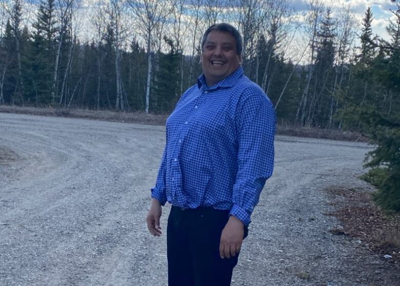 A man stands on a gravel road.