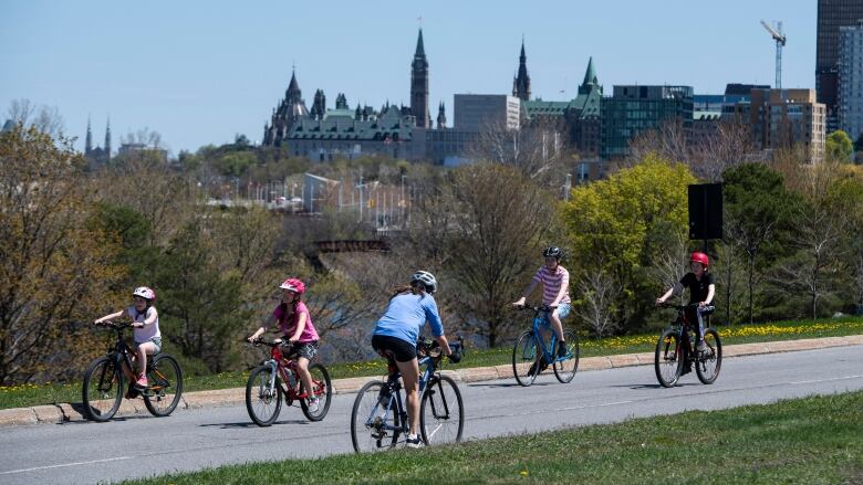 Five people bike on a parkway in a city that's been closed to motor vehicles.