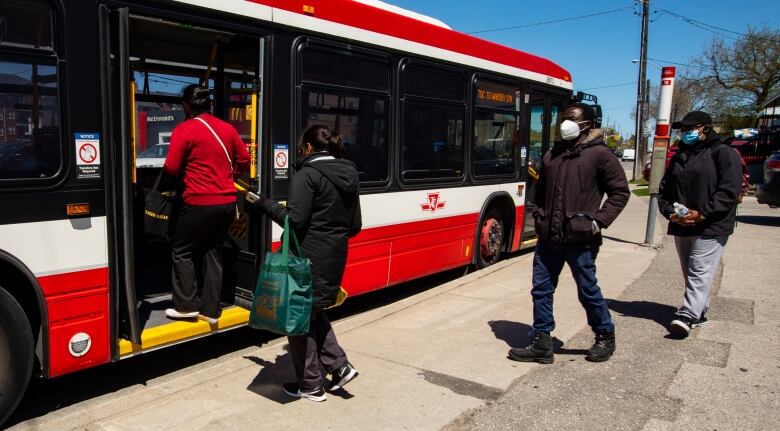 People wait to get on a TTC bus.