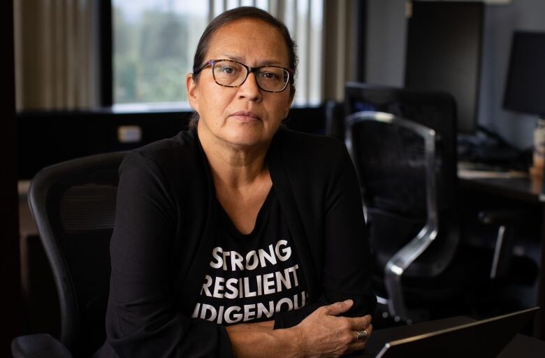 Dr. Wieman looks at the camera wearing a t-shirt the reads, strong, resilient, Indigenous. 