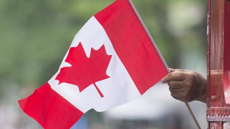 Hand holding a large Canada flag.