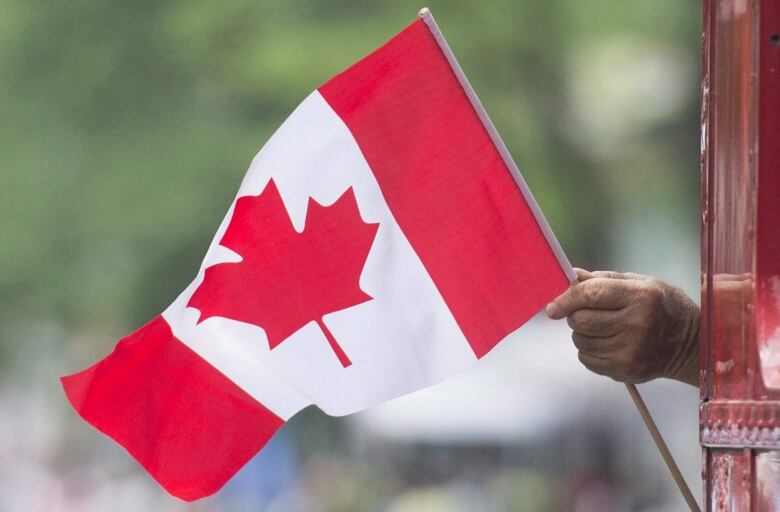 Hand holding a large Canada flag.