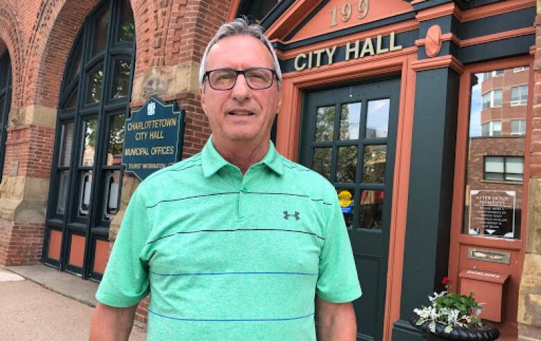 Man in a green golf shirt standing in front of City Hall. 