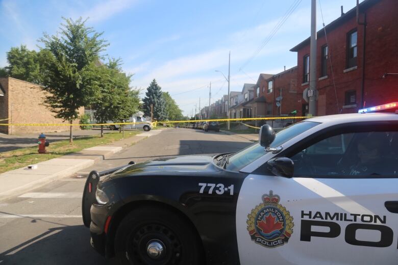 A police car on a street with crime scene tape.