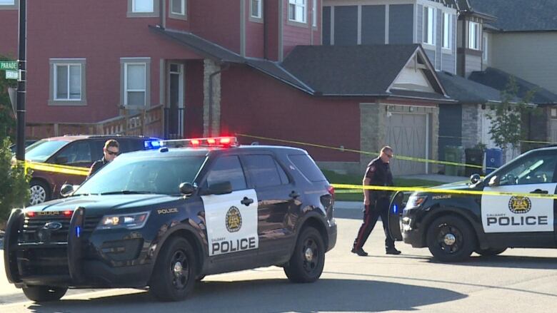 Calgary police officers set up yellow tape around a crime scene. 