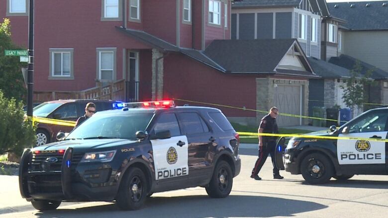 Calgary police officers set up yellow tape around a crime scene. 