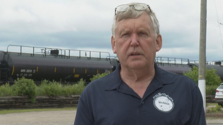 A man with glasses on his head. A train is in the background