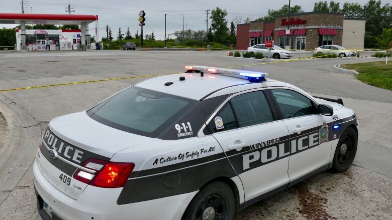 A Winnipeg police cruiser car blocking the vehicle entrance to a Tim Hortons parking lot.