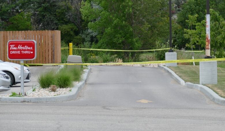 A Tim Hortons drive-thru blocked off with yellow police tape.