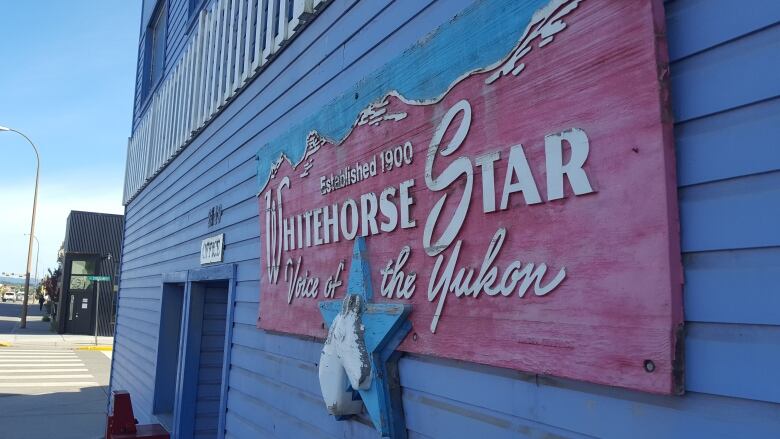 A sign on the side of a building reads, 'The Whitehorse Star.'