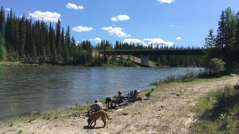 People sit along the edge of a river.