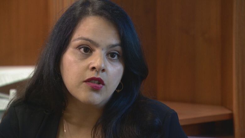 A close-up shot of a woman with long black hair with red lipstick.