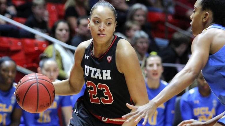 A Black woman in a basketball court dribbling a ball