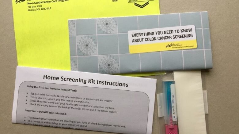 Envelopes and paper and plastic-tubing material with labels describing it as an at-home colon cancer test.