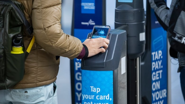 A man taps compass card on a SkyTrain compass card gate. 