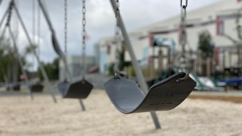 Photo of four empty black swings.