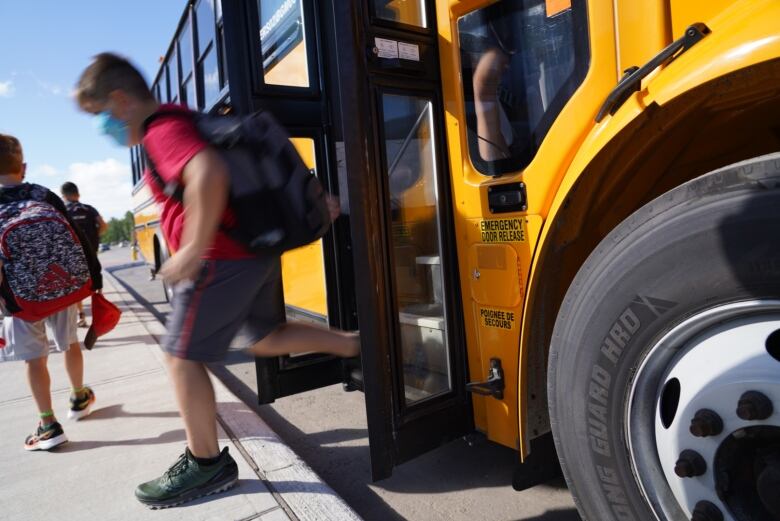 Child walking off the stairs of a school bus. 