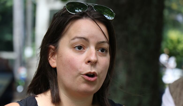 A woman with dark hair and sunglasses pushed up on her head speaks to someone off camera.