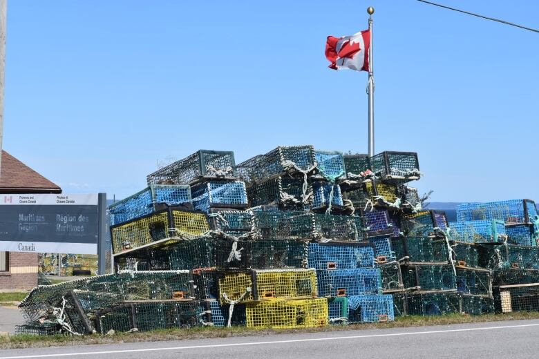 A wall of lobster traps along the side of a road.