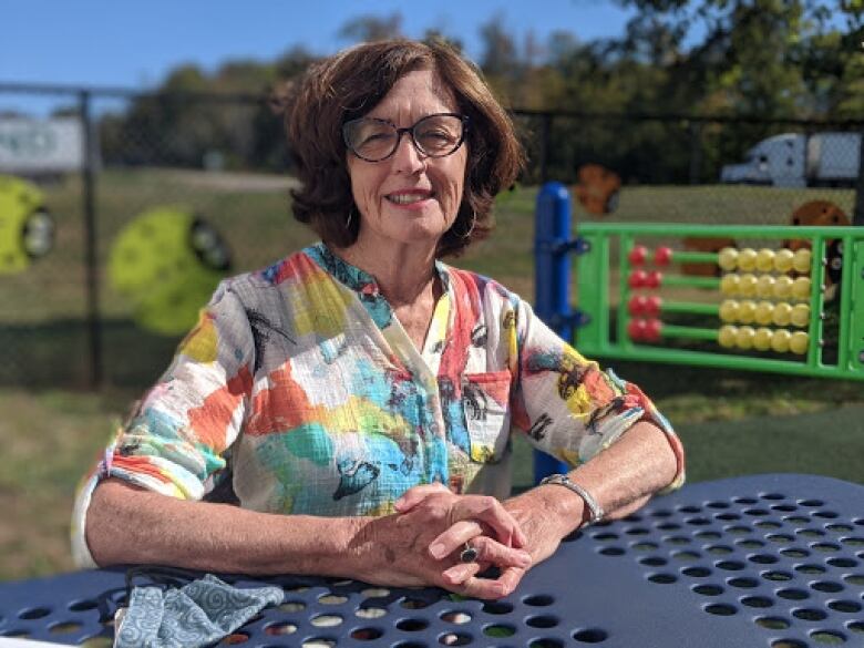 Woman sitting at picnic table in a park. 