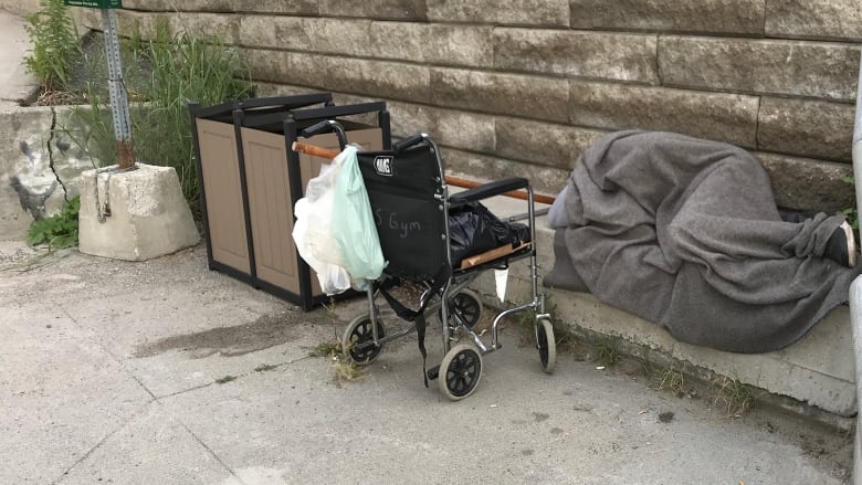 A person wrapped in a blanket sleeping on a concrete slab.