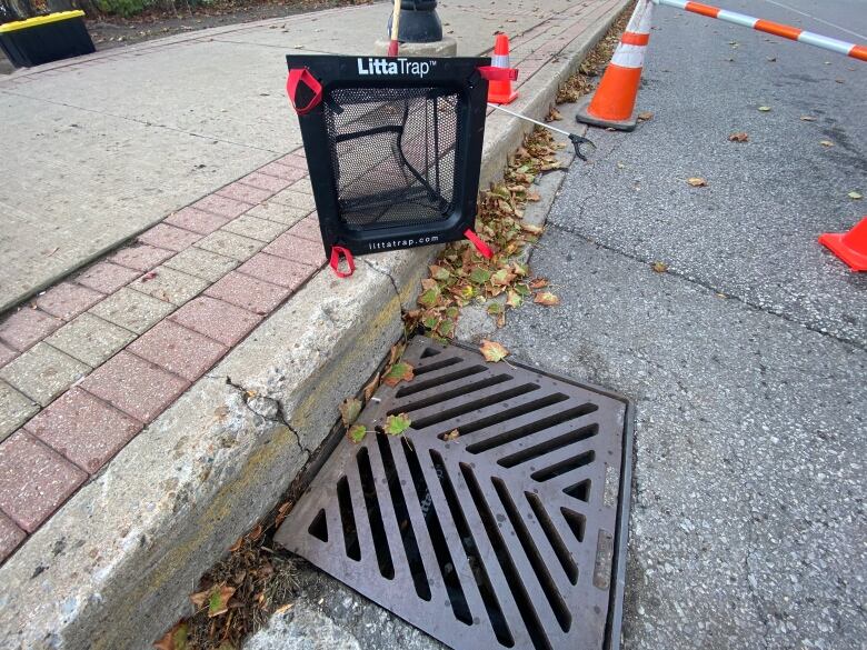 A LittaTrap next to a storm drain. The trap includes a mesh bag that filters garbage out of water.