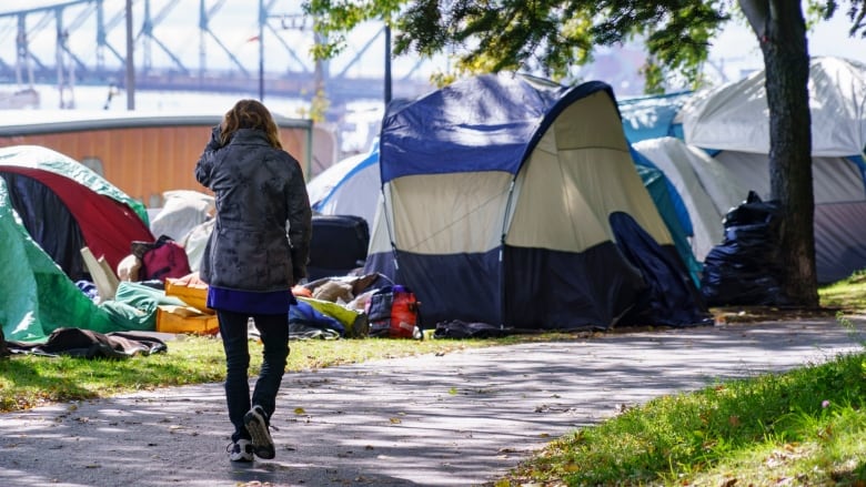 Several homeless encampments set up outside as a woman walks past 