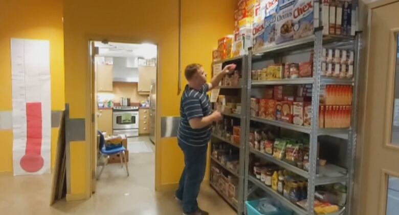 Man standing near shelves of food.