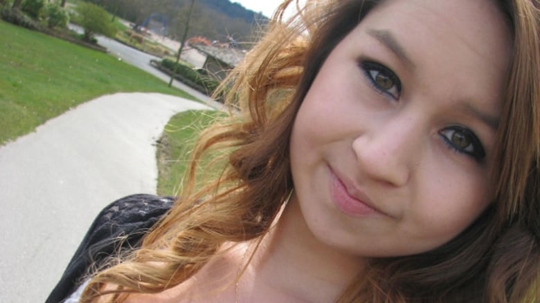 Amanda Todd smiles in a selfie. She is wearing a gold cross and a white top.