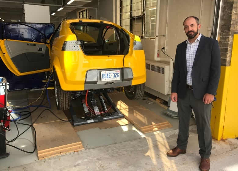 Man standing beside electric vehicle prototype.