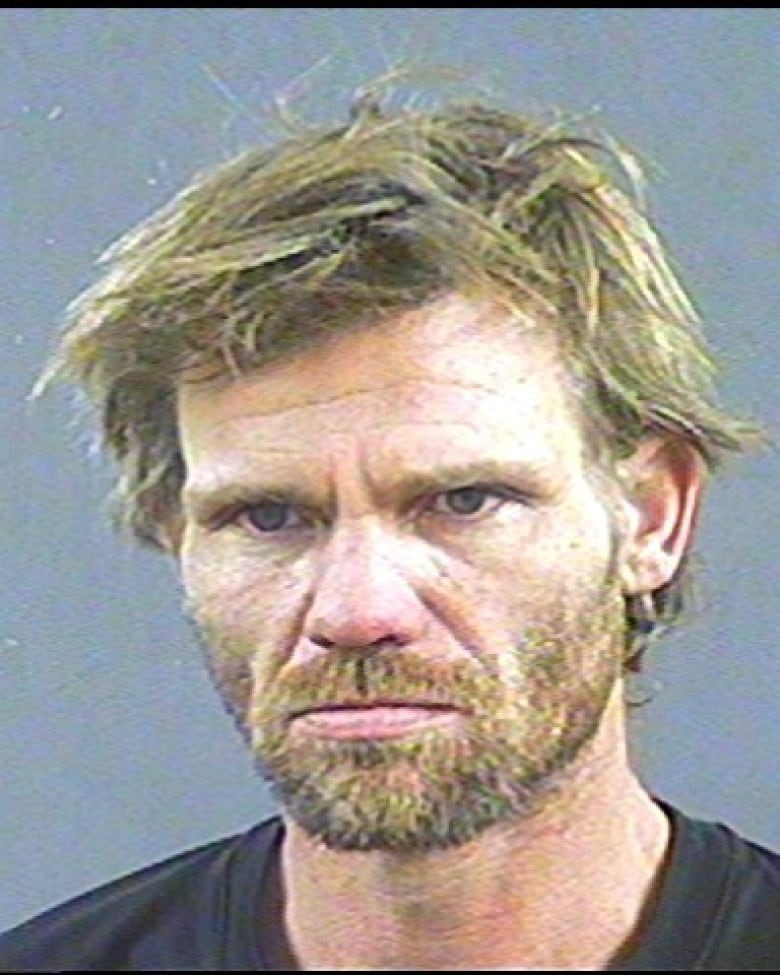 A mugshot of a man with blonde hair and a blonde beard.