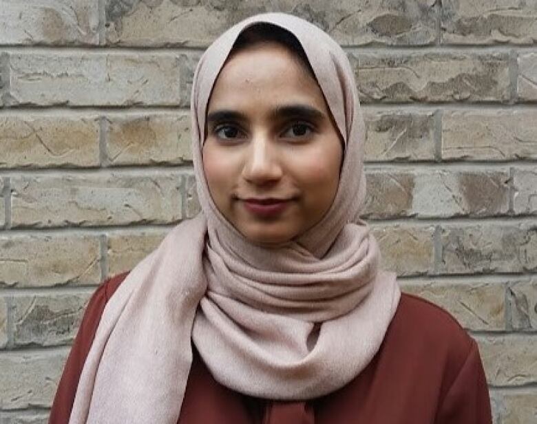 A woman stands against a wall.