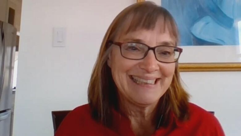 A head-and-shoulders shot of a woman wearing black-rimmed glasses and a red shirt.